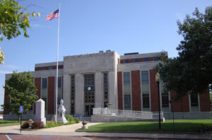 Courthouse building with American flag and trees.